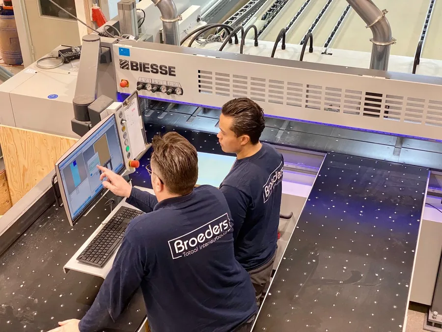 Twee medewerkers van Broeders aan de bediening van de Biesse opdeelzaag